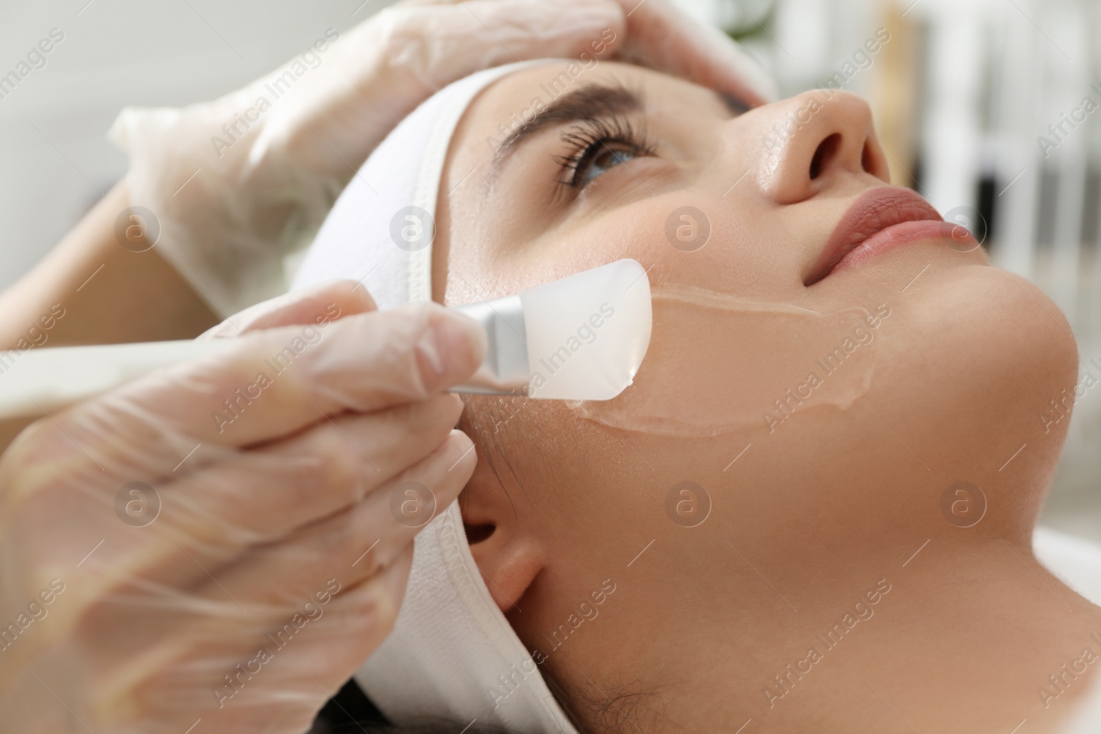 Photo of Young woman during face peeling procedure in salon, closeup