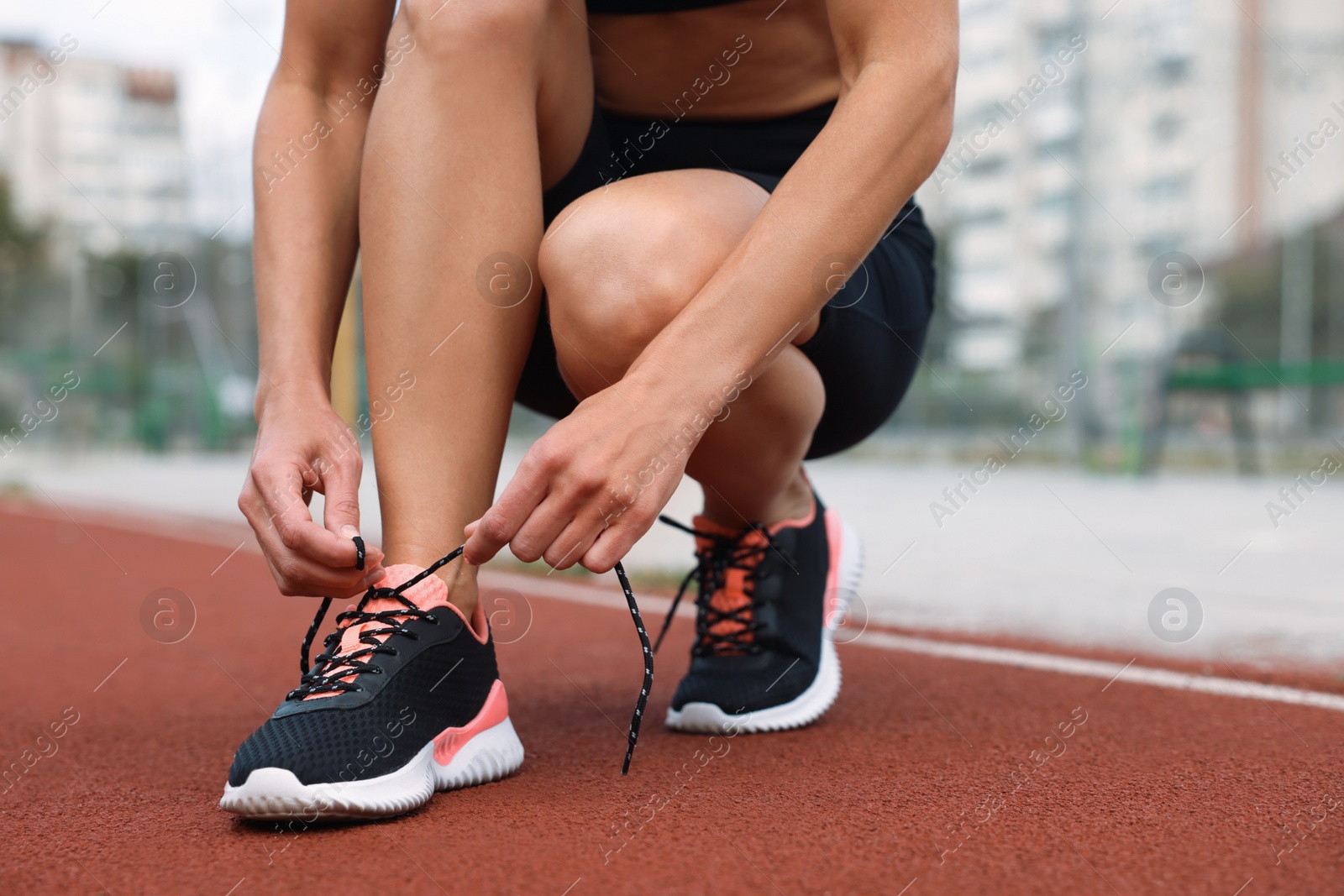 Photo of Woman tying shoelaces before training outdoors. closeup. Space for text