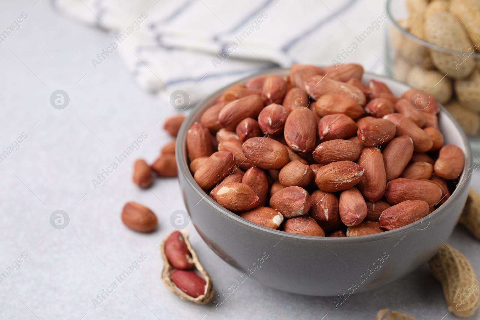 Photo of Fresh unpeeled peanuts in bowl on grey table, closeup. Space for text