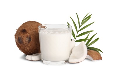 Glass of delicious vegan milk, coconut pieces and green leaves on white background
