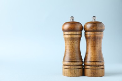 Photo of Wooden salt and pepper shakers on light background, closeup. Space for text