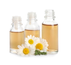 Chamomile flowers and cosmetic bottles of essential oil on white background