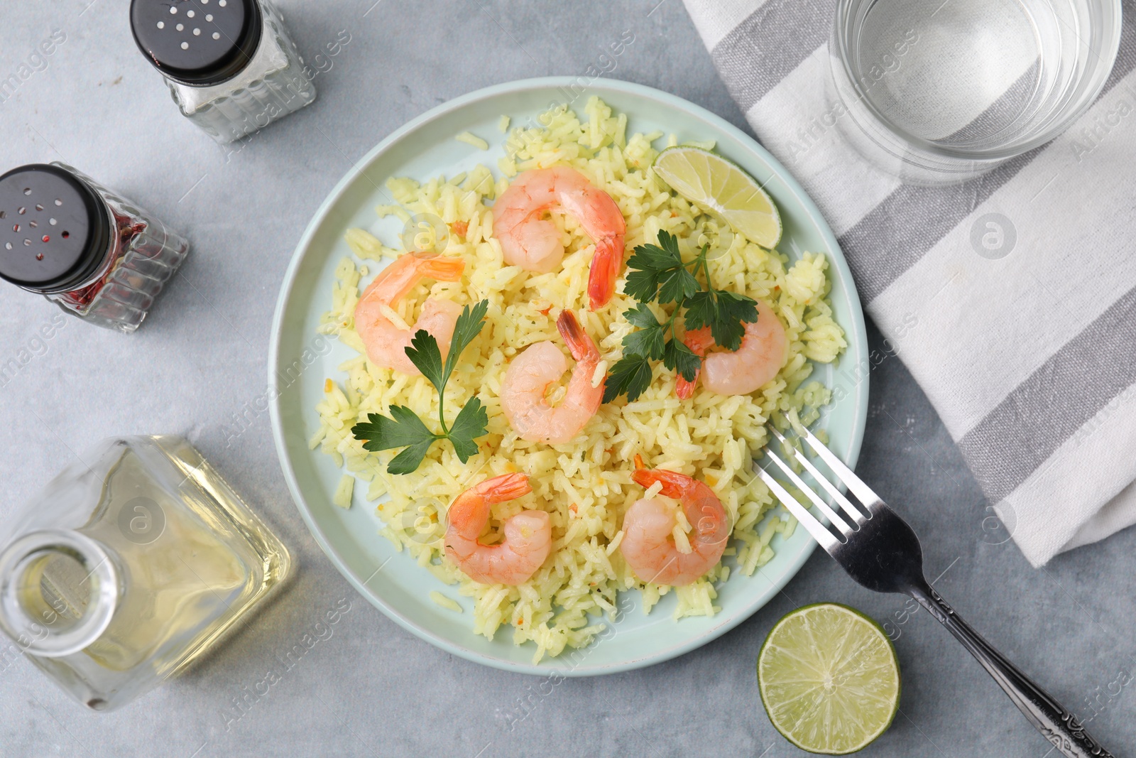 Photo of Delicious risotto with shrimps, lime and parsley served on light grey table, flat lay