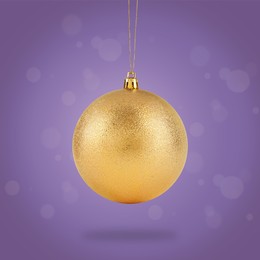 Image of Beautiful golden Christmas ball hanging on violet background