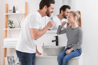 Photo of Father and his daughter brushing teeth together in bathroom