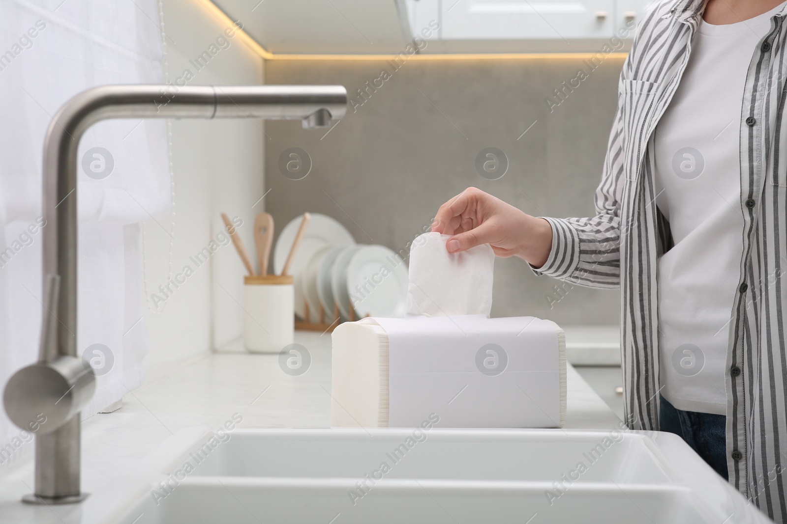 Photo of Woman taking paper towel from package in kitchen, closeup
