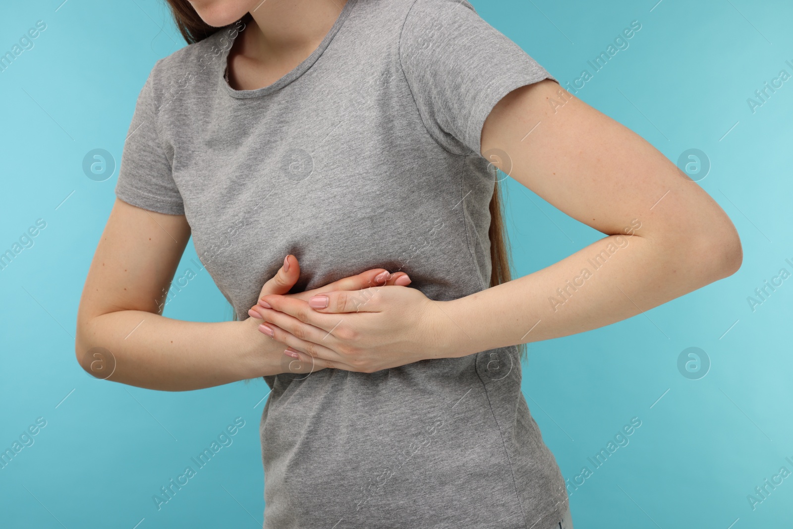 Photo of Woman having heart attack on light blue background, closeup