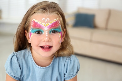 Cute little girl with face painting indoors