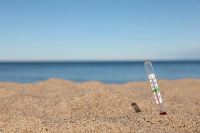 Photo of Weather thermometer in sand near sea, space for text