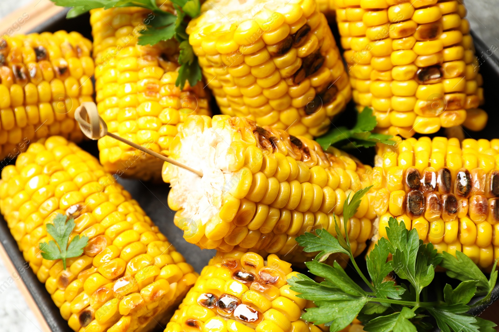 Photo of Tasty grilled corn with parsley, closeup view