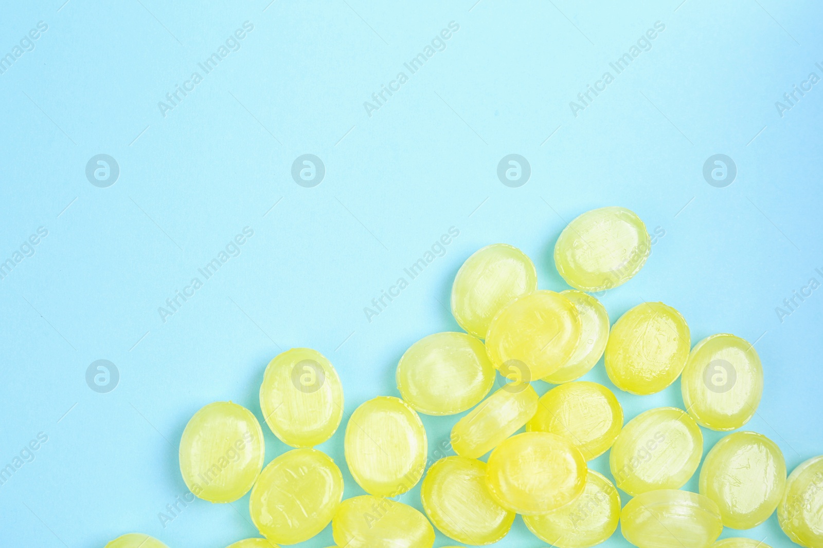 Photo of Many delicious lemon drops on light blue background, flat lay. Space for text