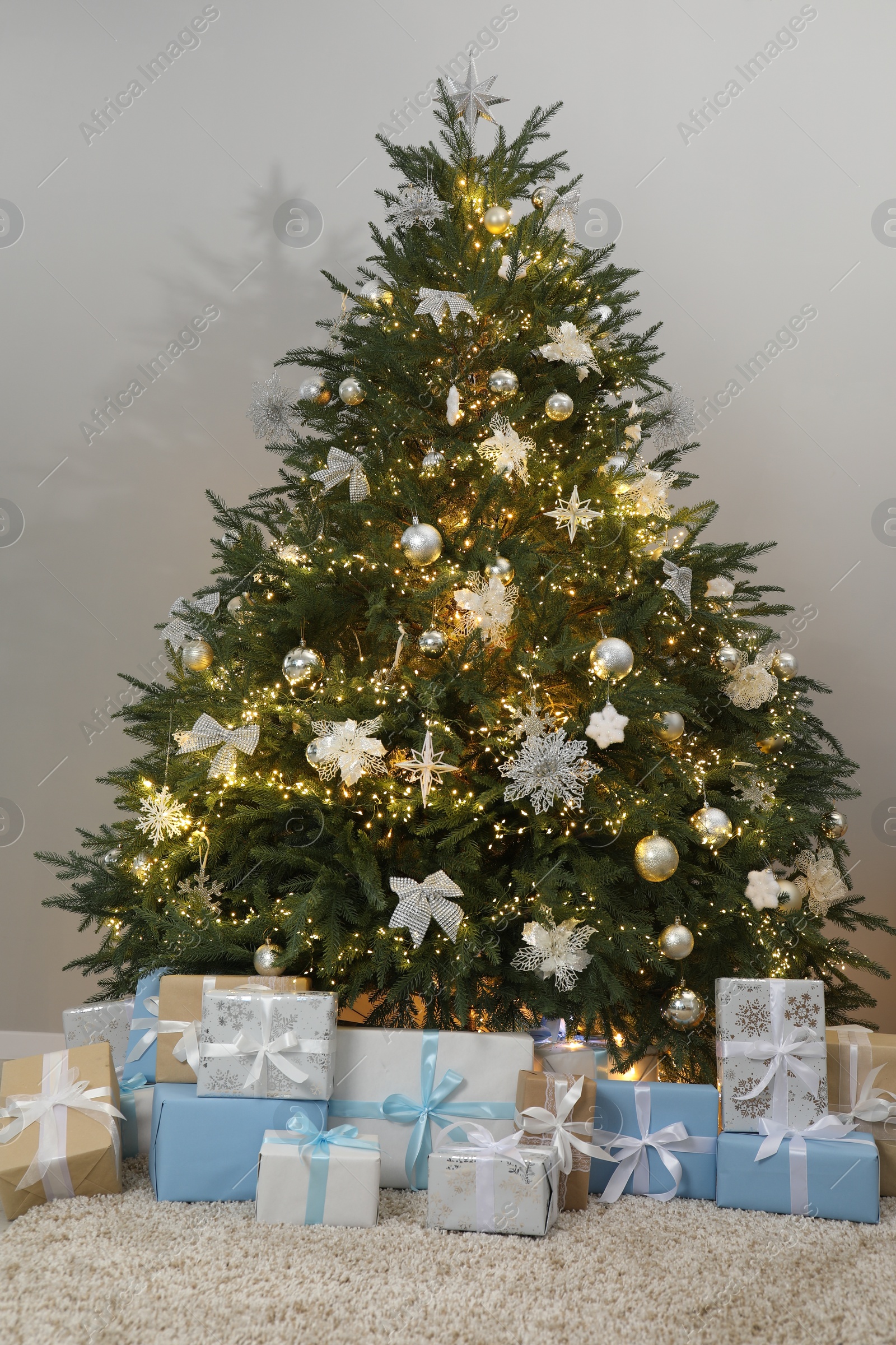 Photo of Many gift boxes under decorated Christmas tree in room