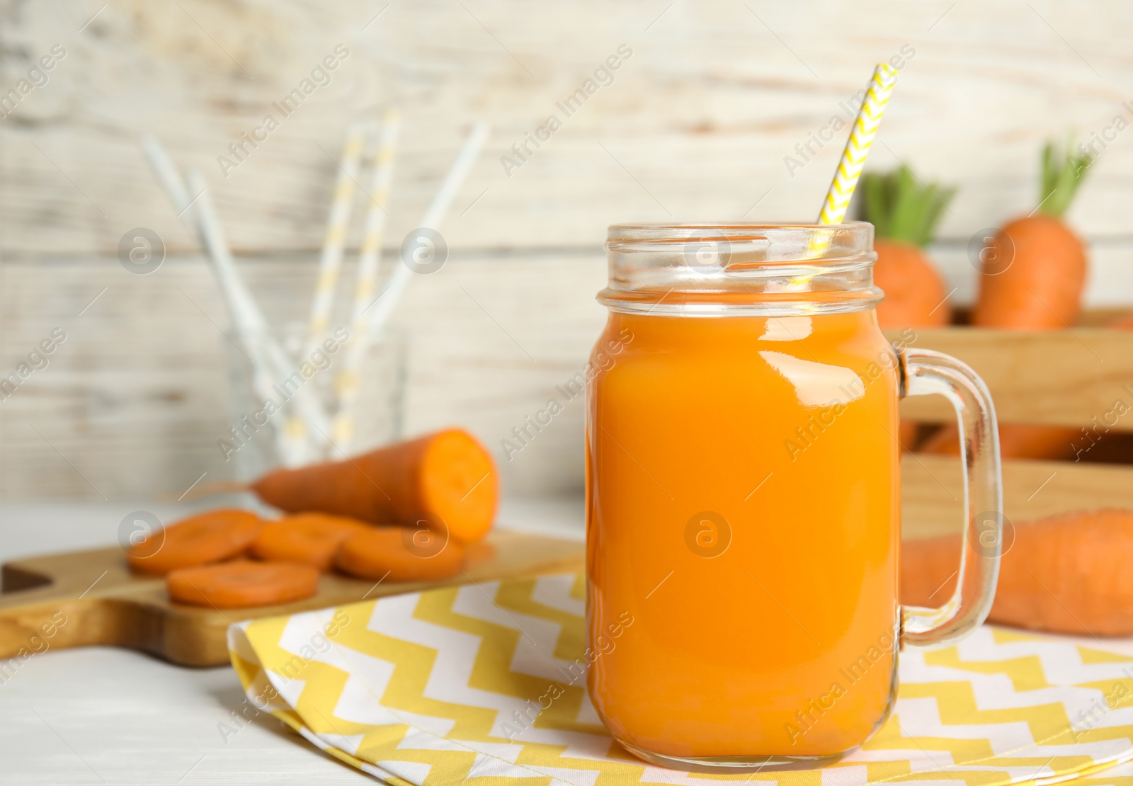 Photo of Freshly made carrot juice in mason jar on white table, space for text