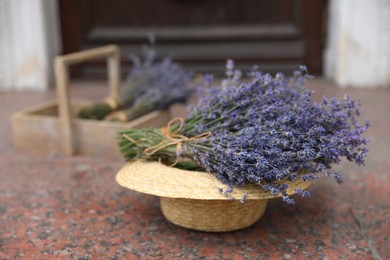 Beautiful lavender flowers and straw hat on marble tiles outdoors