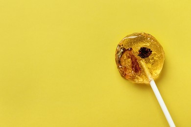 Sweet colorful lollipop with berries on yellow background, top view. Space for text