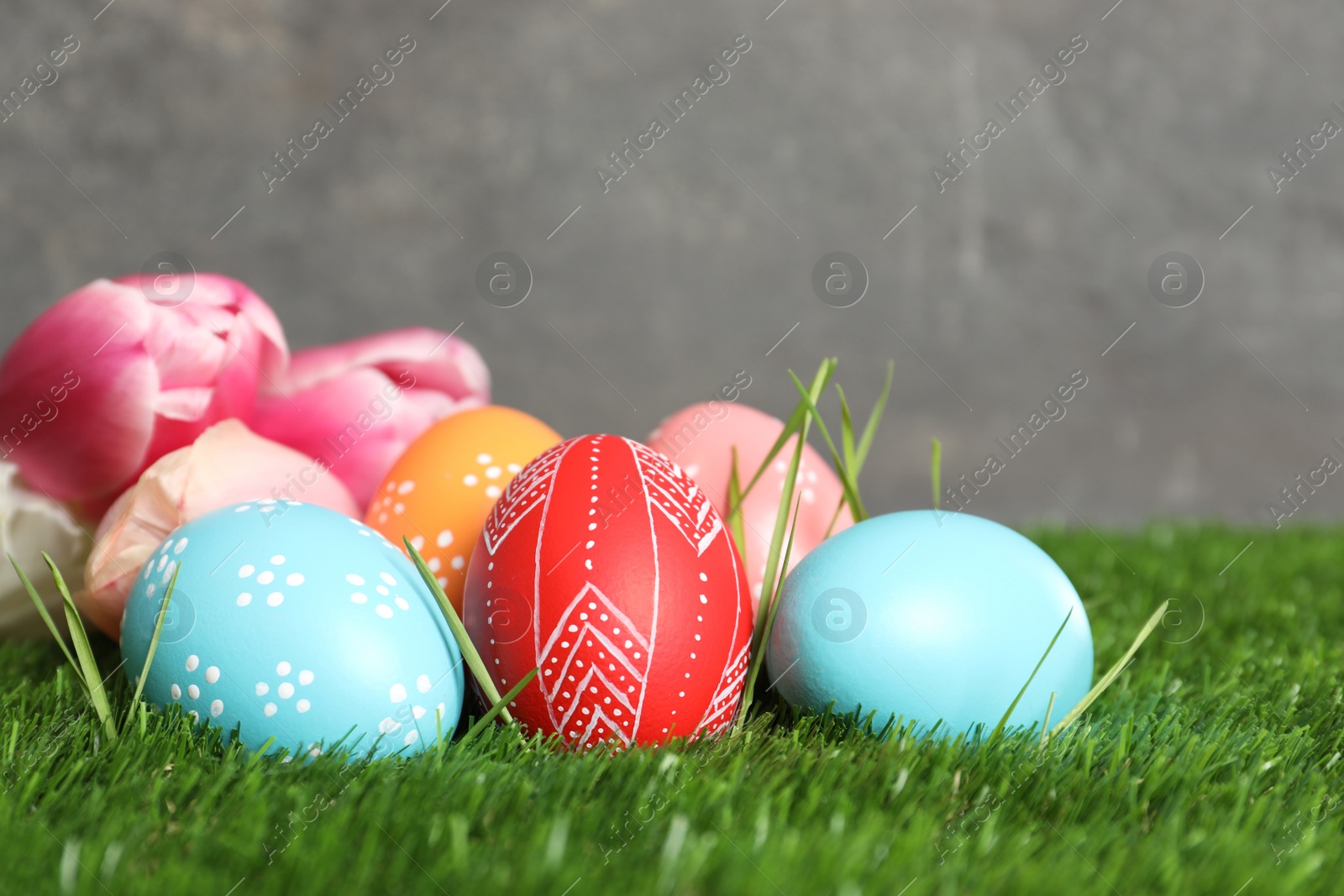 Photo of Painted Easter eggs and spring flowers on green grass