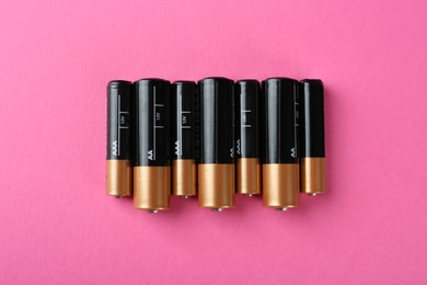 Many different batteries on pink background, flat lay