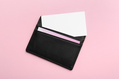 Leather business card holder with blank cards on pink background, top view