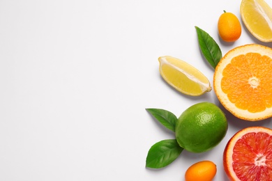 Photo of Fresh juicy citrus fruits with green leaves on light background, flat lay. Space for text