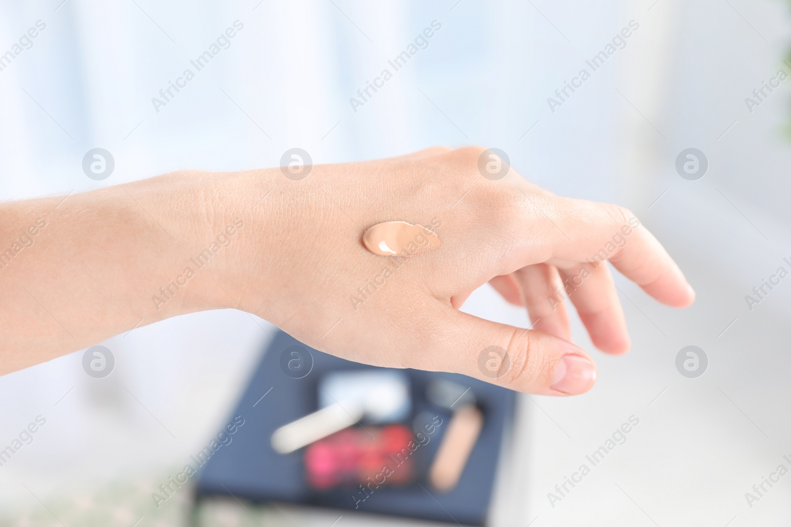 Photo of Woman testing foundation tone on hand, closeup