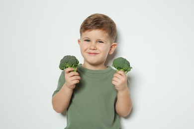 Photo of Adorable little boy with broccoli on white background