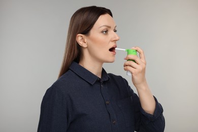 Photo of Woman using throat spray on grey background