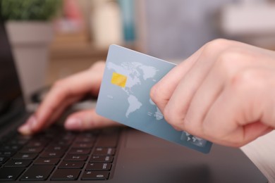 Photo of Online payment. Woman with laptop and credit card at table, closeup