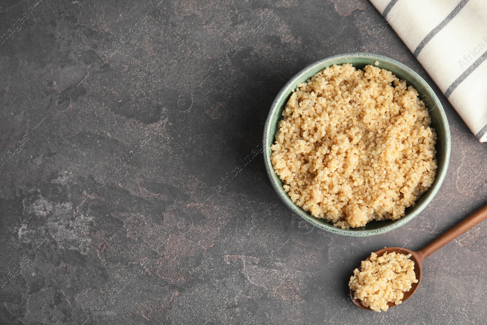 Photo of Composition with cooked quinoa in bowl and wooden spoon on table, top view. Space for text