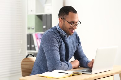 Photo of African American man in glasses working on laptop indoors