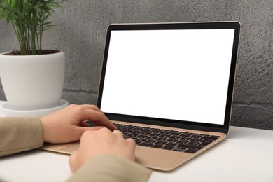 Woman working on laptop at white table, closeup. Mockup for design