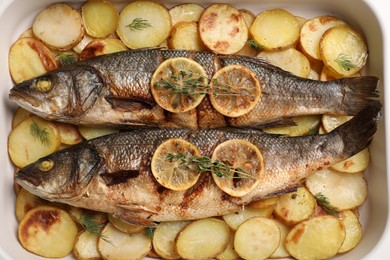 Photo of Baking tray with delicious baked sea bass fish and potatoes, top view