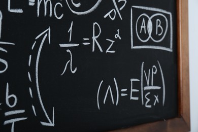 Photo of Blackboard with different physical formulas written with chalk on white wall, closeup