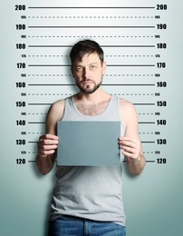 Image of Criminal mugshot. Arrested man with blank card against height chart