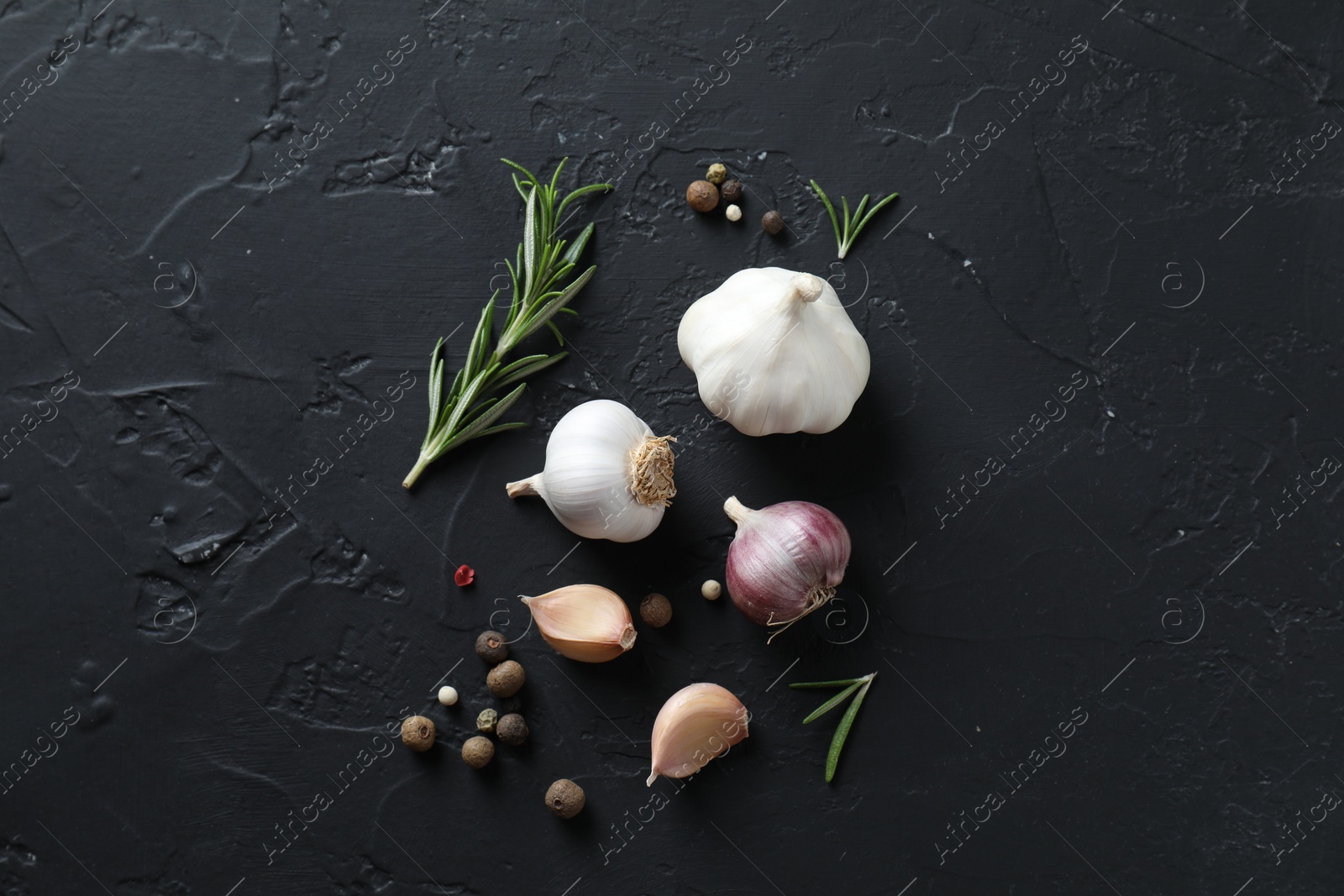 Photo of Fresh raw garlic and spices on black table, flat lay