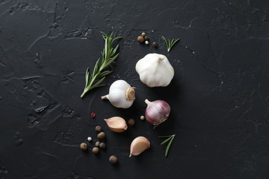 Fresh raw garlic and spices on black table, flat lay