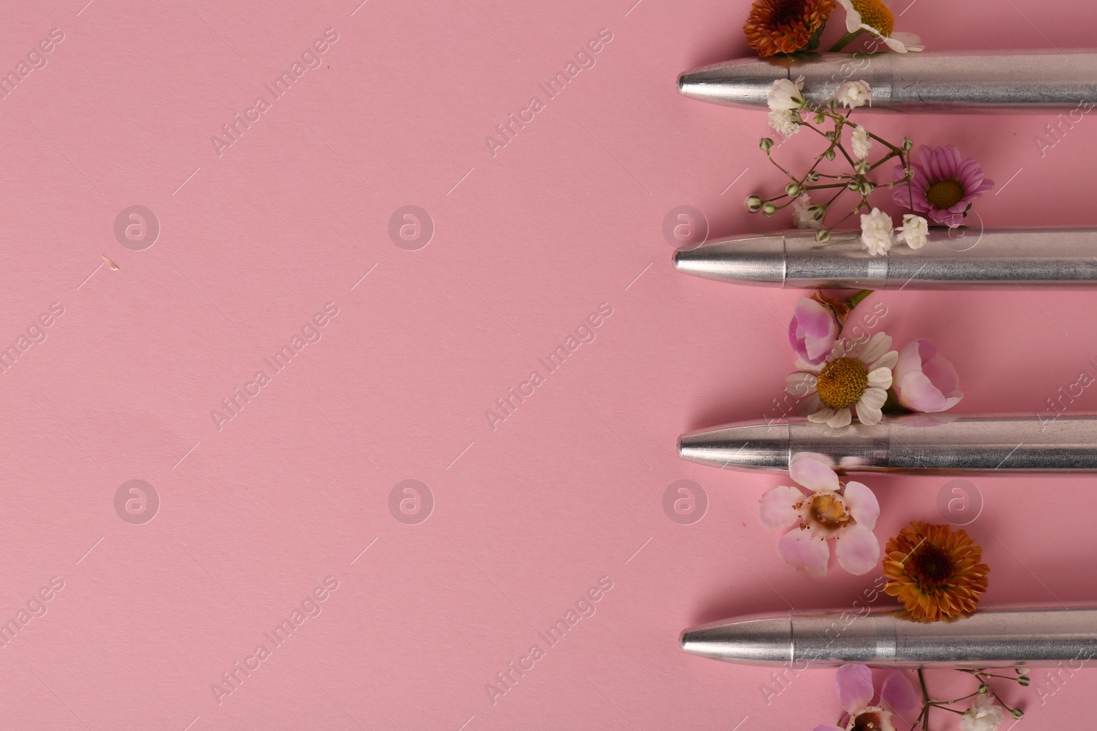 Photo of Bullets and beautiful flowers on pink background, flat lay. Space for text