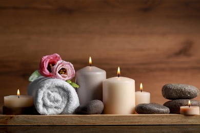 Photo of Beautiful composition with spa stones, flowers and burning candles on mirror table against wooden background