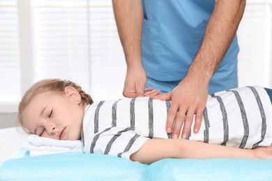 Orthopedist massaging child's back in clinic, closeup. Scoliosis treatment