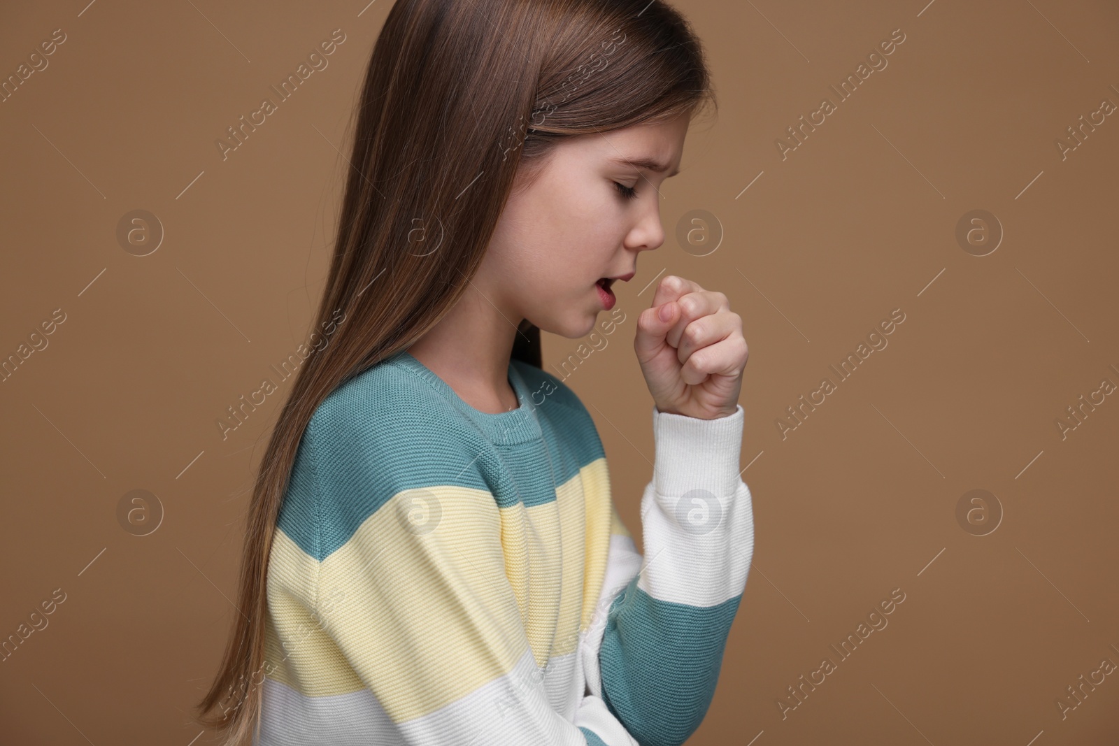 Photo of Sick girl coughing on brown background. Cold symptoms