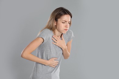 Photo of Woman suffering from nausea on grey background, space for text. Food poisoning