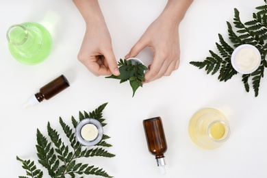 Photo of Female dermatologist creating skin care product on white background, top view