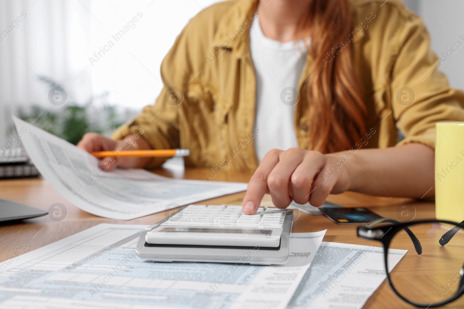 Photo of Woman calculating taxes at wooden table in room, closeup