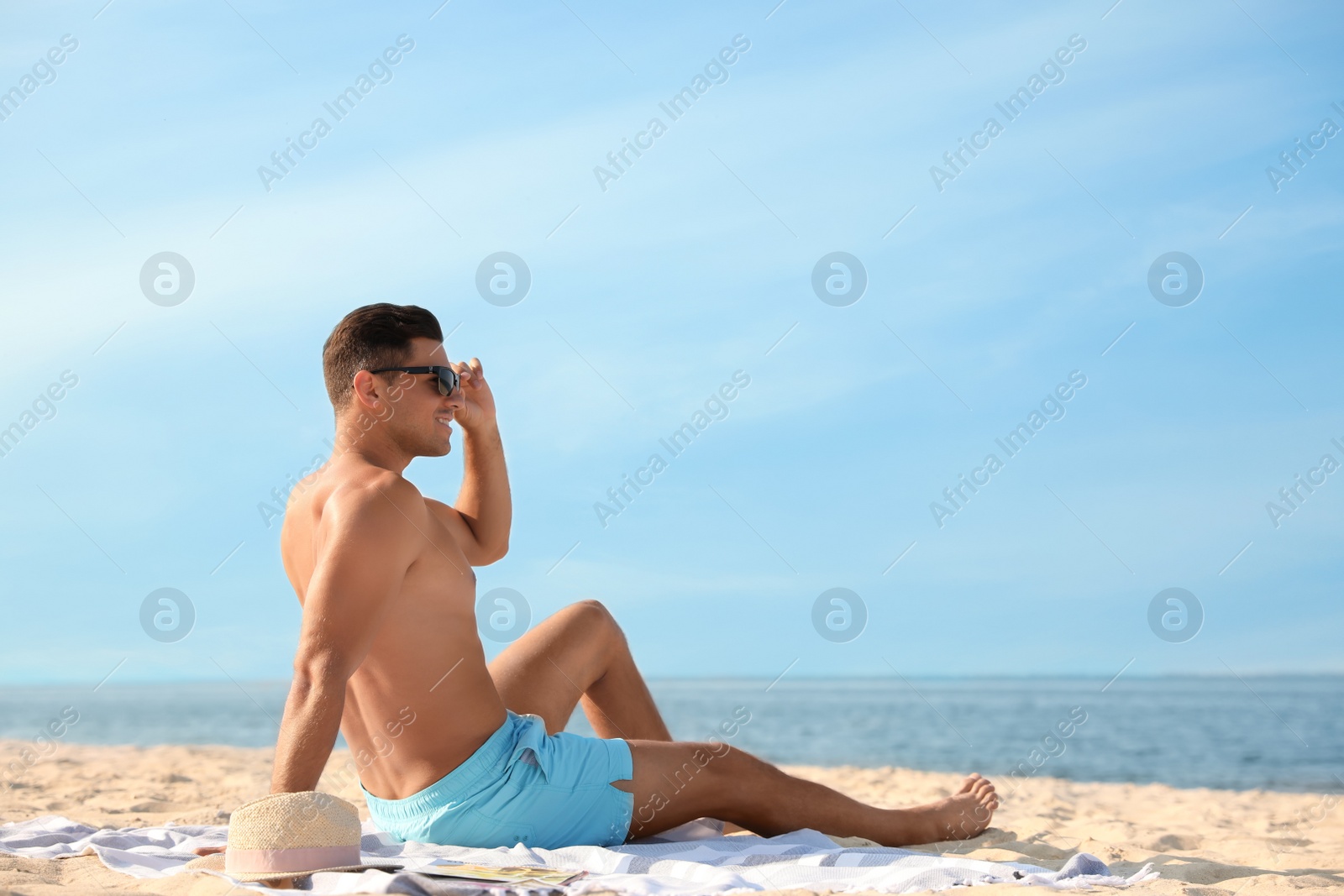 Photo of Happy man with slim body resting on beach. Space for text