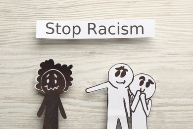 Flat lay composition with phrase Stop Racism and paper figures on white wooden table