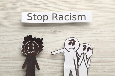 Photo of Flat lay composition with phrase Stop Racism and paper figures on white wooden table