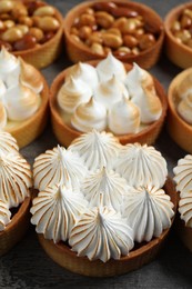 Photo of Many different tartlets on dark grey table, closeup. Tasty dessert