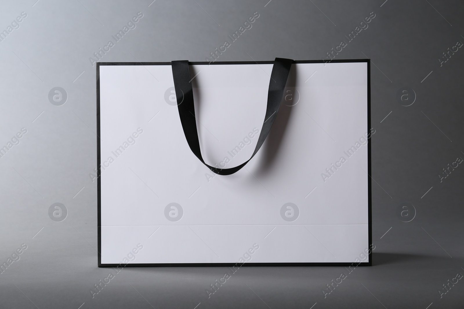 Photo of One paper bag on grey background. Mockup for design