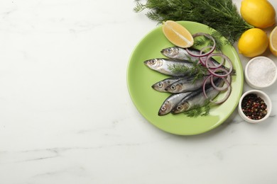 Photo of Fresh raw sprats, cut lemon, onion, dill and spices on white marble table, flat lay. Space for text