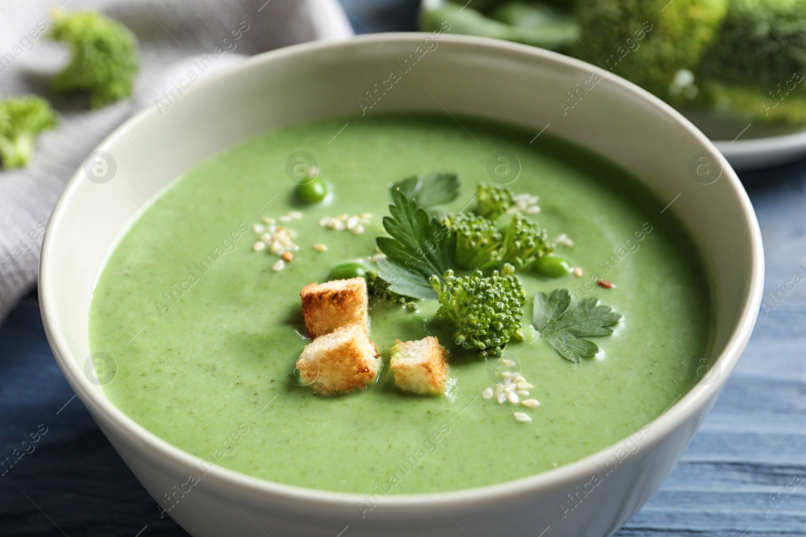 Photo of Fresh vegetable detox soup made of broccoli and green peas with croutons in dish on table, closeup