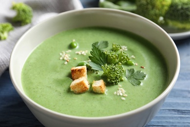 Fresh vegetable detox soup made of broccoli and green peas with croutons in dish on table, closeup